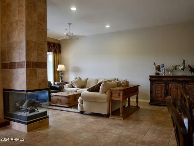 living room featuring a tiled fireplace, ceiling fan, light tile patterned floors, and tile walls