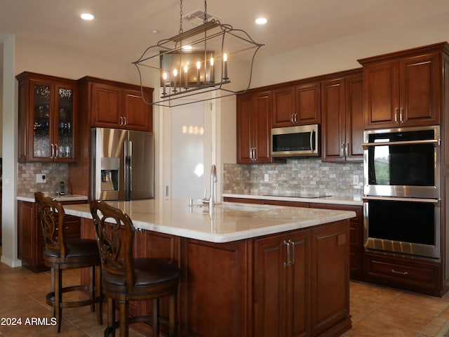 kitchen featuring sink, an inviting chandelier, decorative backsplash, a center island with sink, and appliances with stainless steel finishes