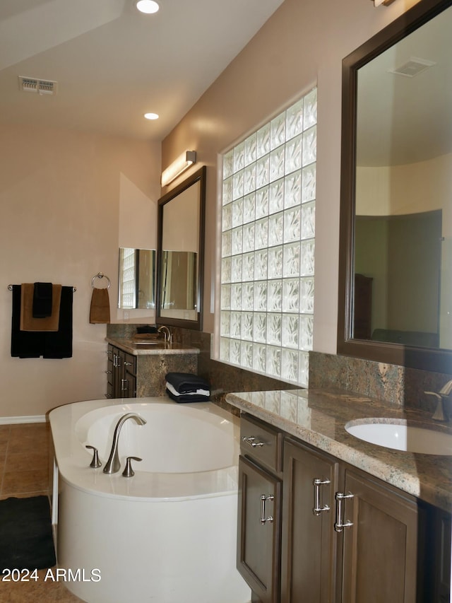 bathroom with vanity, a bathtub, tile patterned floors, and a wealth of natural light