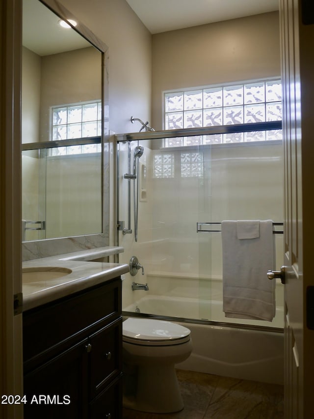 full bathroom featuring shower / bath combination with glass door, vanity, tile patterned floors, and toilet