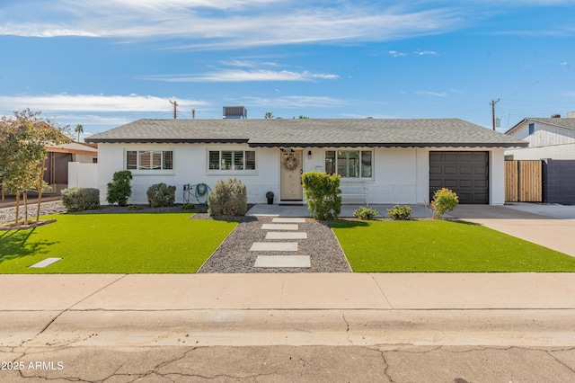 ranch-style home with roof with shingles, fence, a garage, driveway, and a front lawn