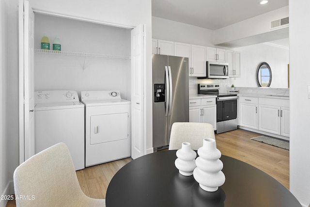 kitchen featuring white cabinets, tasteful backsplash, stainless steel appliances, and washing machine and clothes dryer