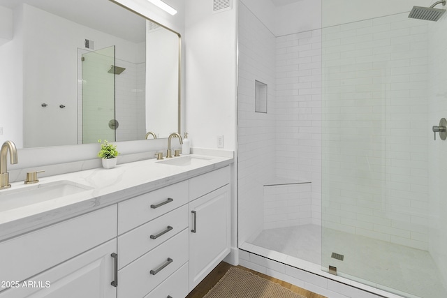 bathroom featuring tiled shower and vanity