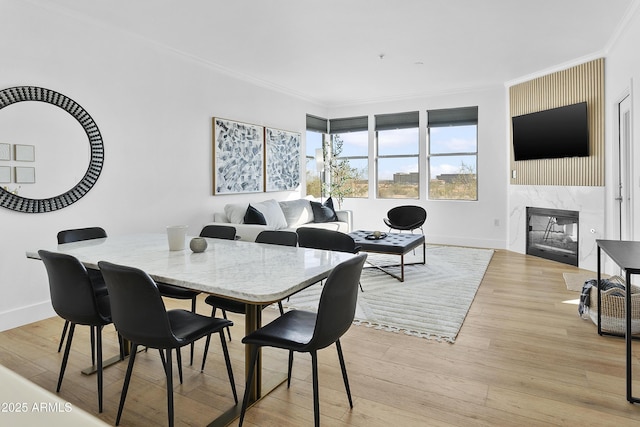 dining room featuring light hardwood / wood-style floors, crown molding, and a premium fireplace