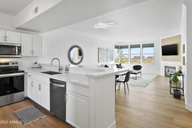 kitchen with kitchen peninsula, sink, white cabinets, and stainless steel appliances