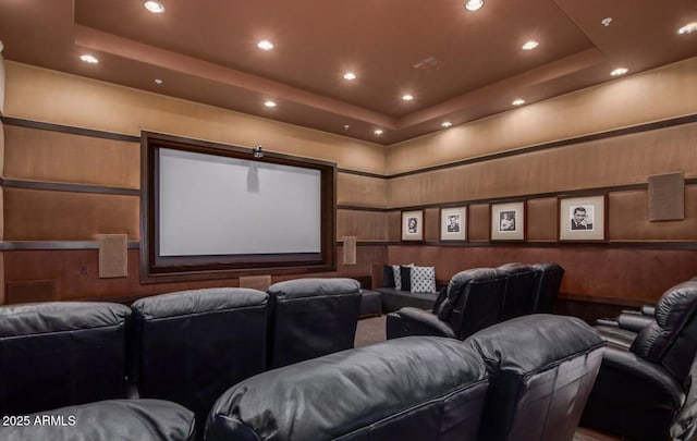 cinema room featuring a raised ceiling and wooden walls