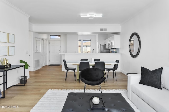 living room with light wood-type flooring and ornamental molding