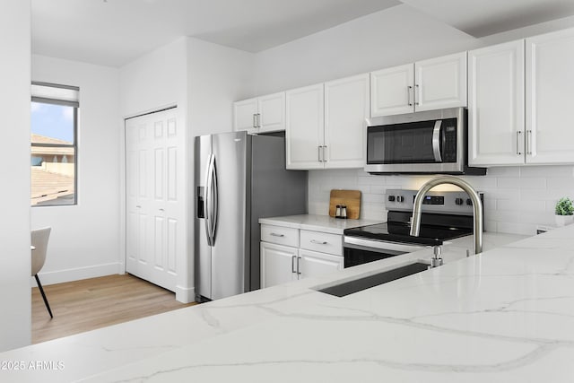 kitchen featuring white cabinets, light stone counters, and appliances with stainless steel finishes