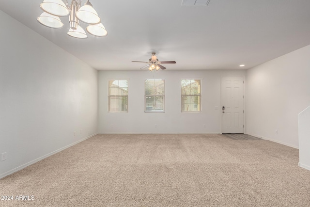 carpeted empty room featuring ceiling fan with notable chandelier