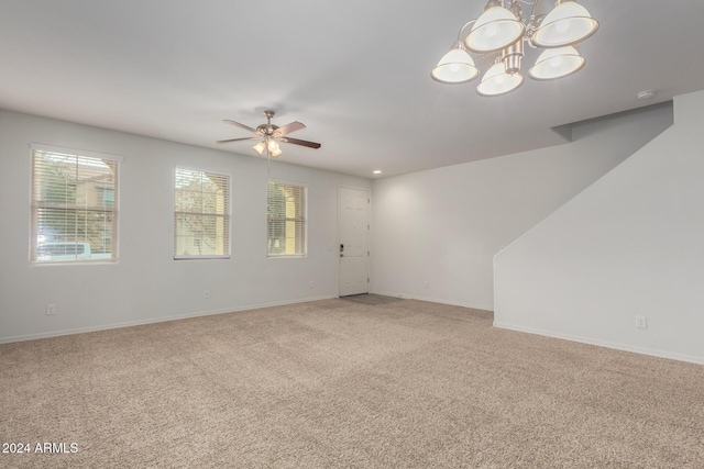 empty room with carpet flooring and ceiling fan with notable chandelier