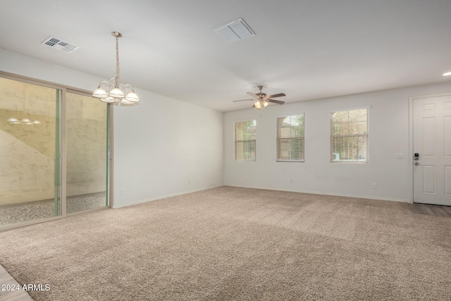 carpeted spare room with ceiling fan with notable chandelier