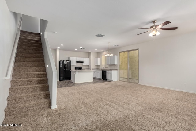 unfurnished living room with carpet flooring and ceiling fan with notable chandelier