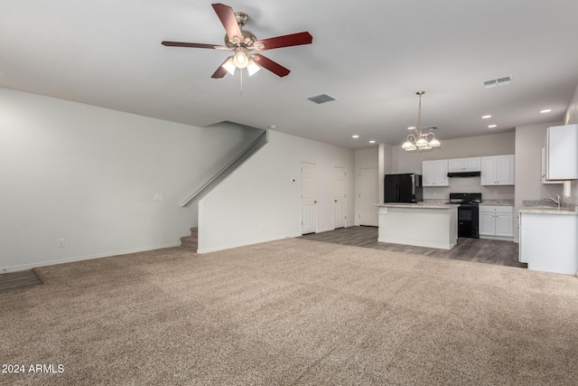 interior space with ceiling fan with notable chandelier, a kitchen island, black appliances, decorative light fixtures, and white cabinetry