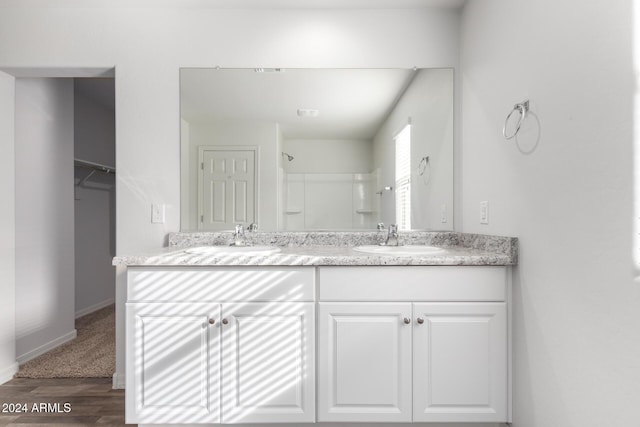 bathroom with walk in shower, vanity, and hardwood / wood-style flooring