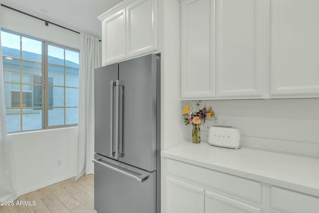 kitchen with white cabinets, high end fridge, and light hardwood / wood-style flooring