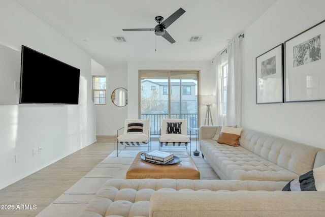 living room featuring light wood-type flooring, ceiling fan, and a wealth of natural light