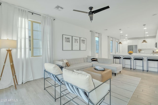 living room with light wood-type flooring and ceiling fan