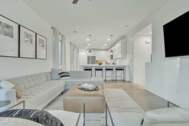 living room featuring sink, light hardwood / wood-style flooring, and ceiling fan