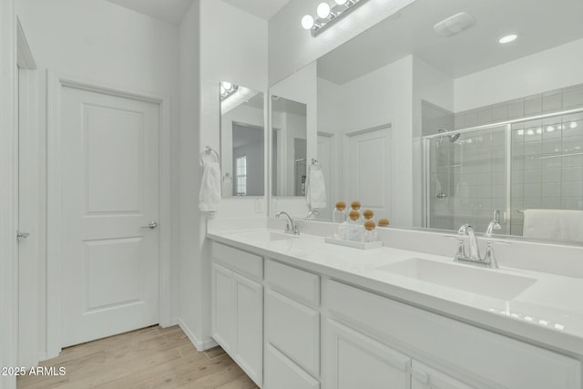 bathroom featuring hardwood / wood-style floors, a shower with door, and vanity