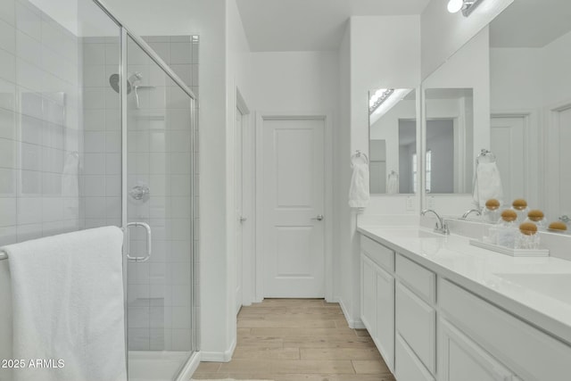 bathroom with hardwood / wood-style floors, a shower with door, and vanity