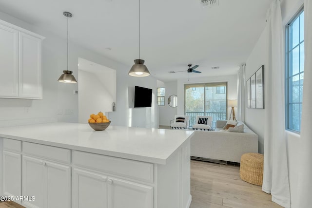 kitchen with ceiling fan, hanging light fixtures, white cabinets, and light wood-type flooring