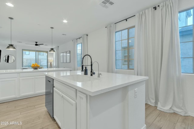 kitchen with sink, hanging light fixtures, and a center island with sink