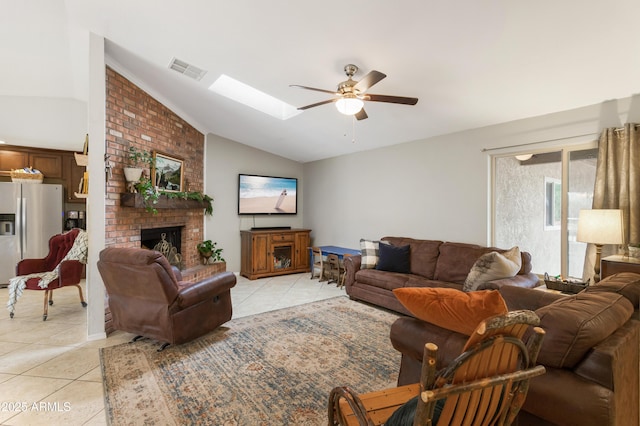 tiled living room featuring a fireplace, lofted ceiling with skylight, and ceiling fan