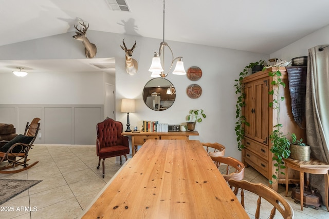 tiled dining space with vaulted ceiling and an inviting chandelier