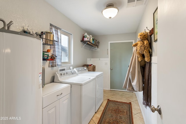 laundry room featuring water heater, light tile patterned floors, and washer and dryer