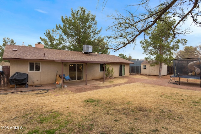 back of house featuring central AC, a yard, a patio, a trampoline, and a shed