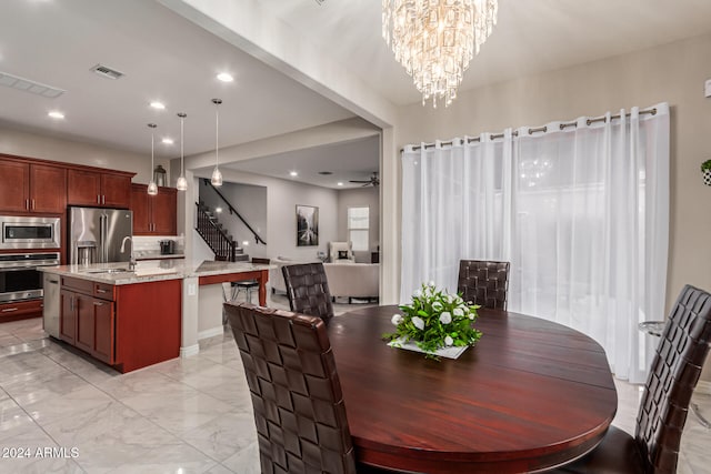 dining space featuring ceiling fan with notable chandelier and sink