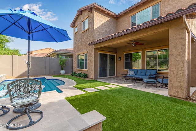 back of property with a fenced in pool, a patio area, outdoor lounge area, a lawn, and ceiling fan