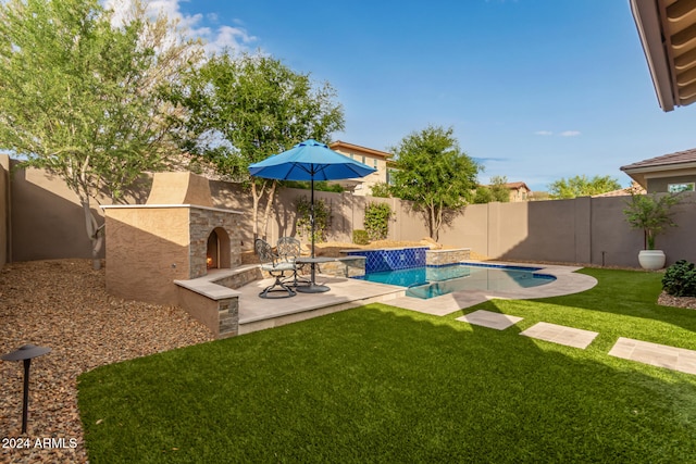 view of pool with a yard, an outdoor stone fireplace, and a patio area