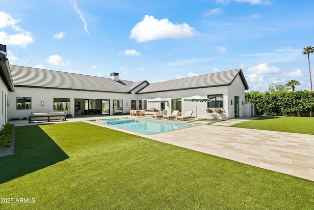 rear view of house featuring outdoor lounge area, a patio, a tiled roof, and a yard