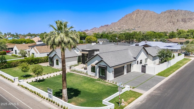 view of front facade with stucco siding, driveway, a residential view, a garage, and a mountain view