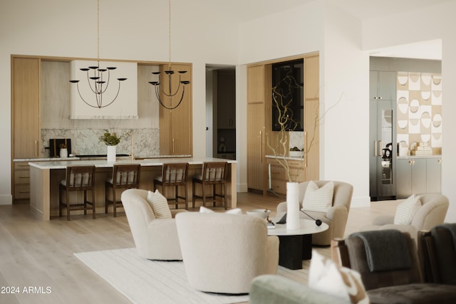 living room featuring a high ceiling, light wood-type flooring, and an inviting chandelier