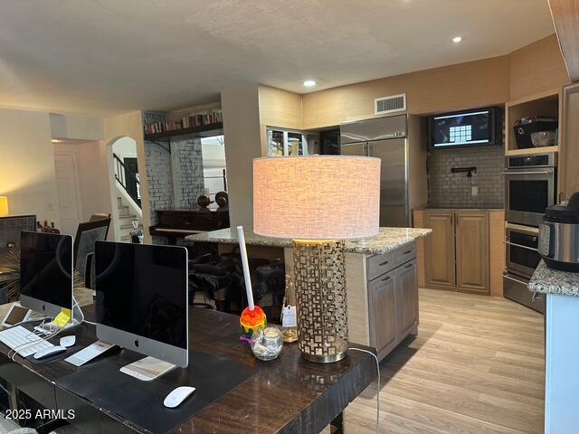 11028 W Crimson Ln, Avondale, AZ 85392 - kitchen with light wood-style floors, light stone countertops, a warming drawer, stainless steel appliances, and recessed lighting