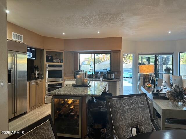 11028 W Crimson Ln, Avondale, AZ 85392 - kitchen with stainless steel appliances, beverage cooler, light stone countertops, a sink, and a kitchen island