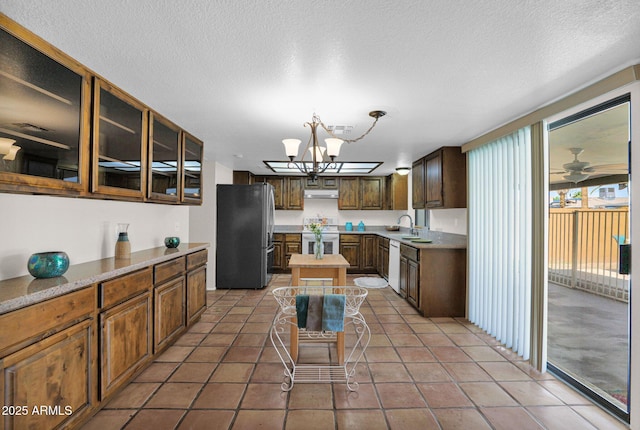 kitchen with glass insert cabinets, a notable chandelier, white appliances, under cabinet range hood, and light countertops
