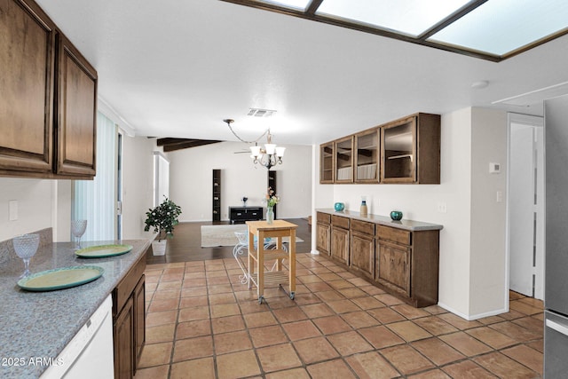 kitchen featuring glass insert cabinets, visible vents, light countertops, light tile patterned flooring, and white dishwasher