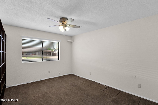 spare room with a textured ceiling, baseboards, a ceiling fan, and dark carpet