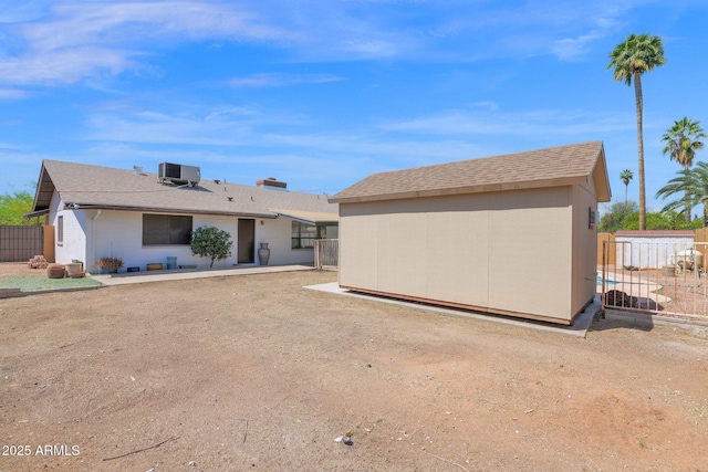 back of house featuring fence, cooling unit, a patio, an outdoor structure, and a storage shed