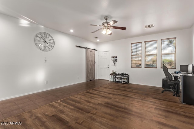 unfurnished office with dark hardwood / wood-style flooring, a barn door, and ceiling fan