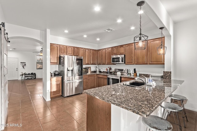 kitchen with sink, a breakfast bar area, hanging light fixtures, kitchen peninsula, and stainless steel appliances