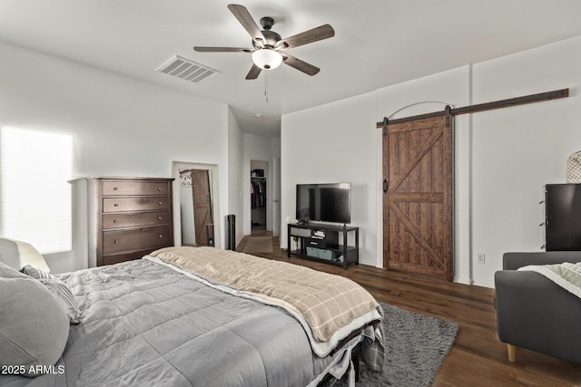 bedroom featuring dark hardwood / wood-style floors, a barn door, and ceiling fan