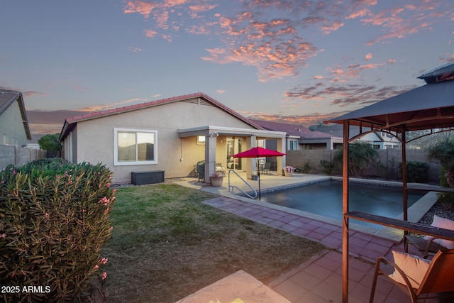 back house at dusk featuring a fenced in pool, a gazebo, a yard, and a patio area