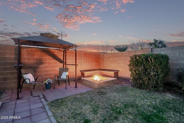 yard at dusk featuring a gazebo, an outdoor fire pit, and a patio