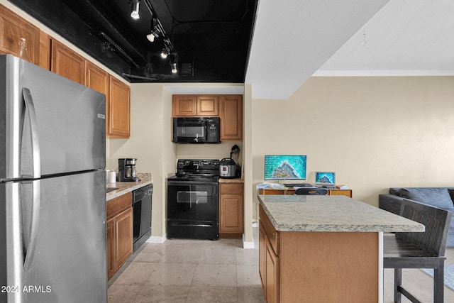 kitchen featuring a breakfast bar, track lighting, black appliances, ornamental molding, and a kitchen island