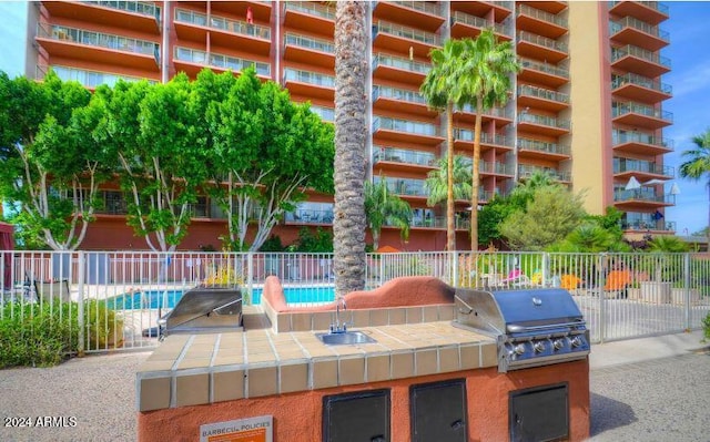 view of patio / terrace featuring a community pool, area for grilling, a grill, and sink