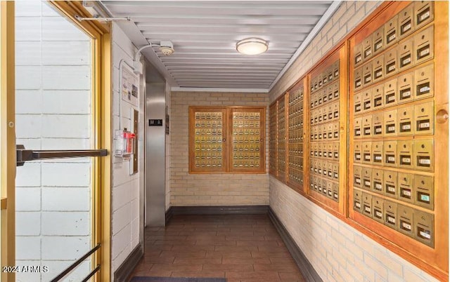 corridor with mail boxes, dark hardwood / wood-style flooring, and brick wall